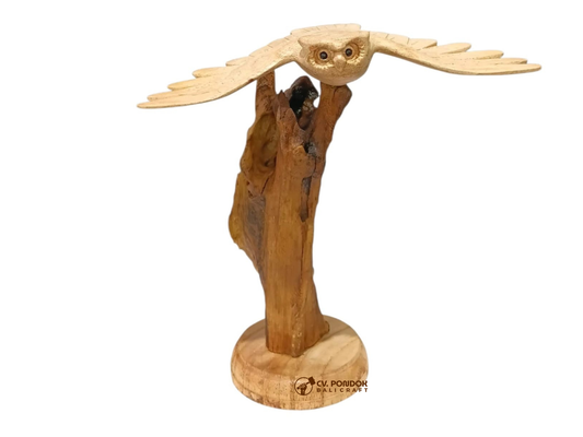 Hand-carved wooden flying owl with extended wings displayed on a natural rootwood trunk and round wooden base