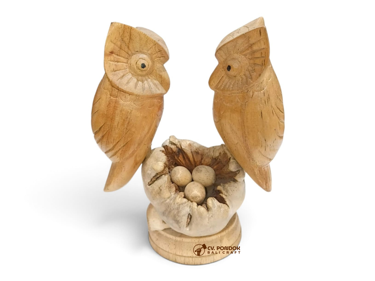 Hand-carved wooden owl couple standing beside a natural nest containing three wooden eggs on a round base