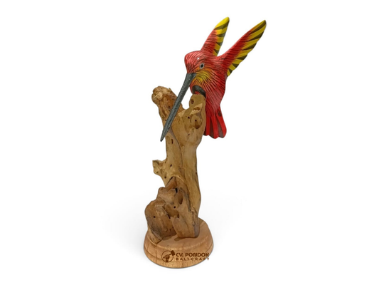 Hand-painted red wooden hummingbird with raised wings and a long beak displayed on natural rootwood